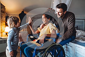 Happy multiethnic family. Smiling little girl with disability in wheelchair at home photo