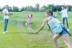 happy multiethnic teenage friends playing with flying disc