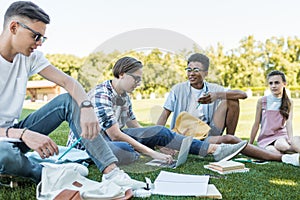 happy multiethnic teenagers sitting and talking while studying together