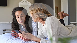 Happy multiethnic women friends using phone at home