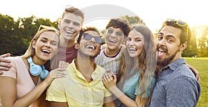 Happy multiethnic young friends taking selfie portrait while walking in summer park.