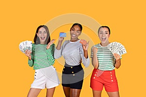 Happy multiethnic young women holding cash and credit cards