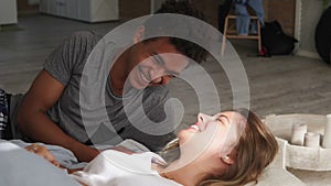 Happy multiethnical couple lying in bed and laughing. Waking up together in the morning. Attractive young man and woman