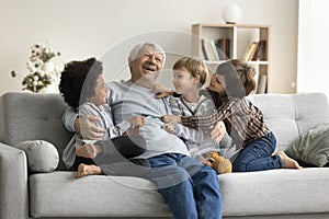 Happy multigenerational family enjoy playtime seated on sofa at home