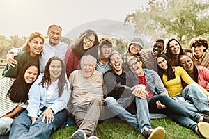 Happy multigenerational people having fun sitting on grass in a public park