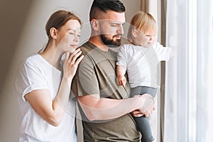 Happy multinational family father young man and mother with baby girl little daughter having fun near window room at home