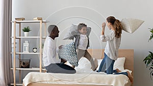 Happy multinational family pillow fight in bedroom