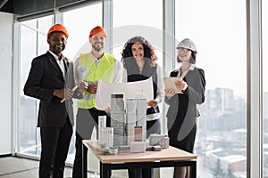 Happy multiracial architects, engineers and designers standing near skyscrapers buildings maquette