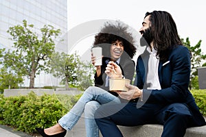 Happy multiracial business people having a lunch break outside office