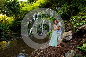 Happy multiracial couple hugging. Mixed couple in love near waterfall in tropical forest. Romantic relation. Wana Amertha