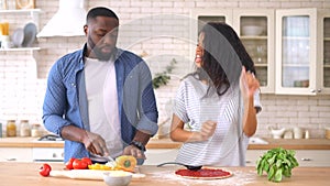 Happy multiracial couple preparing pizza together at home