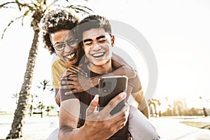 Happy multiracial couple using smart mobile phone device outside - Multiethnic man and woman with youth watching cellphone