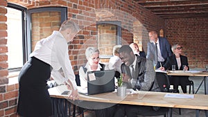 Happy multiracial employees involved in teamwork in workplace with laptops.