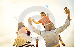 Happy multiracial families group with parents and children playing with kite at beach vacation - Summer joy concept