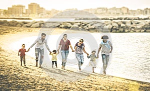 Feliz multirracial familias correr común sobre el Playa sobre el atardecer 