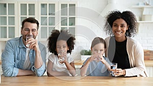 Happy multiracial family drinking pure mineral water in kitchen