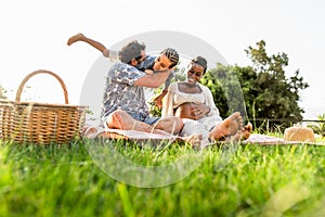 Happy multiracial family having fun together while doing picnic in park