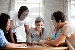 Happy multiracial friends assembling puzzle jigsaw together