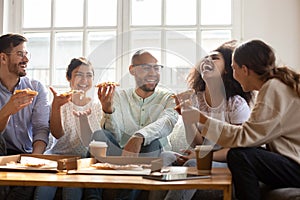 Happy multiracial friends enjoying home party time, eating pizza.