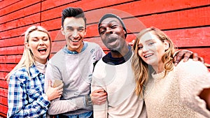 Happy multiracial friends taking group selfie at red wood background - Millenial people sharing fun stories on social media