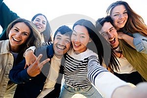 Happy multiracial group of young friends taking a selfie together outdoors