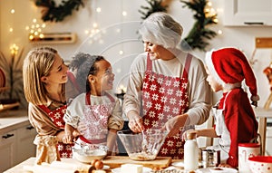 Happy multiracial kids help grandmother to cook Christmas cookies in kitchen during winter holidays