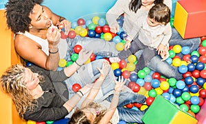 Happy multiracial mom and dad playing with daughter at gameroom photo