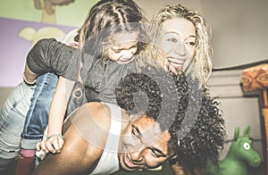 Happy multiracial mom and dad playing with mixed race daughter