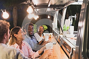 Happy multiracial people buying meal from food truck kitchen