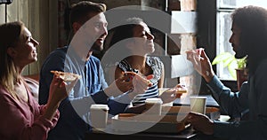 Happy multiracial people students laughing eating pizza together in cafe