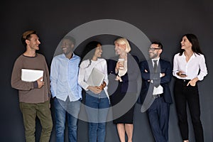 Happy multiracial professional business people laughing standing near wall