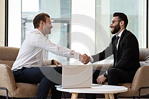 Smiling international businessmen handshake closing deal at meeting