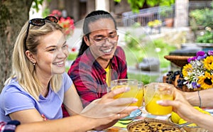 Happy multiratial group of friends having breakfast brunch on a picnic table outdoor in the nature. close up portrait of a woman photo