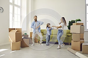 Happy mum, dad and child dancing and having fun in their new house on moving day