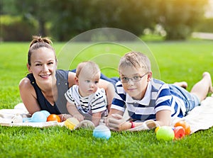 Happy mum and her children playing in park together