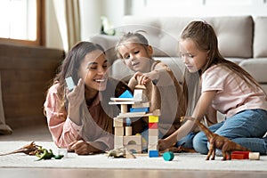 Happy mum with kids daughters playing toys on floor photo