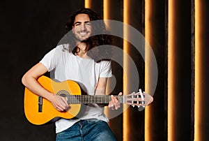 Happy Musician Man Holding And Playing Acoustic Guitar In Studio