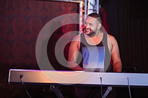 Happy musician playing piano at nightclub