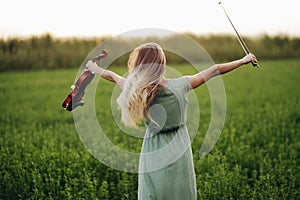 Happy musician violinist holding violin in her hands in sunset light