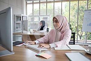 Happy Muslim business woman in traditional clothing smiling and working in office