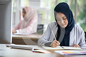 Happy Muslim business woman in traditional clothing smiling and working in office