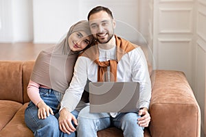 Happy Muslim Couple Sitting With Laptop Hugging Posing At Home