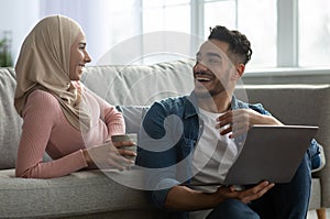 Happy muslim family choosing furniture online, using laptop