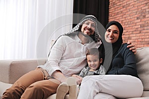 Happy Muslim family spending time together on sofa at home