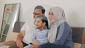 Happy muslim family watching tv. Asian father and mother spending quality time with their baby girl daughter watching movie