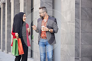 Happy muslim woman and boy freind with city shopping hand holding paper bags