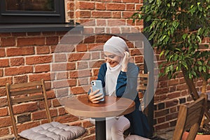Happy muslim woman having video call on smartphone in city