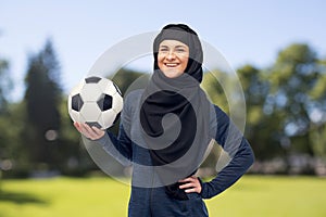 Happy muslim woman in hijab with football