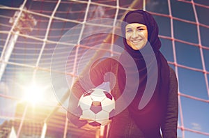 Happy muslim woman in hijab over football goal
