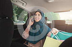 Happy muslim woman talking on smartphone in car